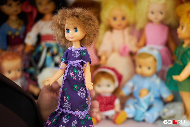 — Вот Оксана. Редчайшая кукла. Я эту дюймовочку три года искала, ждала. Но до сих пор не могу найти ткань, чтобы сшить для нее точно такое же платье, в котором она вышла с фабрики. Пока только такой сиреневый материал нашла | Источник: Роман Данилкин / 63.RU