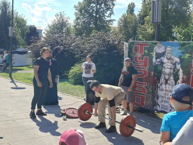 Отец Алексий (слева с микрофоном) наблюдает за попытками воронежцев поднять штангу | Источник: Алена Воропаева / Voronezh1.ru