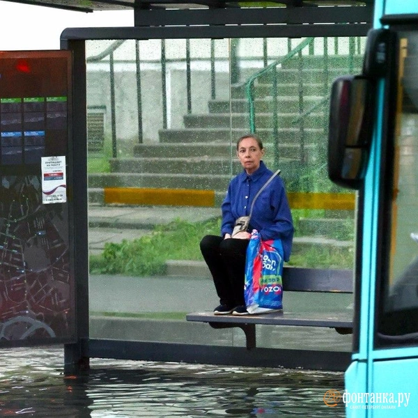 Женщина застряла на остановке после сильного ливня, на улице Уточкина. Ливень подтопил несколько улиц в Приморском районе | Источник: Сергей Михайличенко / FONTANKA.RU