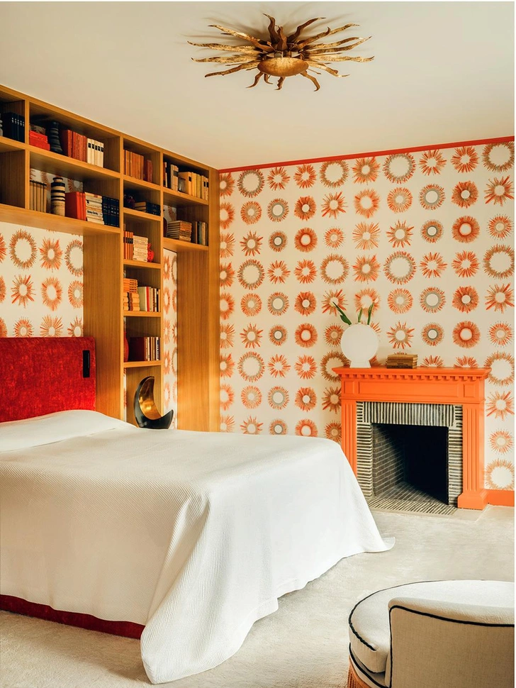 Обои Sunny, дизайн Виктории-Марии Гейер для Pierre Frey. Потолочный светильник в форме солнца, Höllander. Дубовый стеллаж изготовлен на заказ. Изголовье кровати обито бархатом Capri II Granatа, Pierre Frey. Шелковый ковер цвета слоновой кости. Прикроватные лампы в форме луны, Höllander. Белая ваза 1940-х годов на камине, Pol Chambost. | Источник: Клеман Вайсьер
