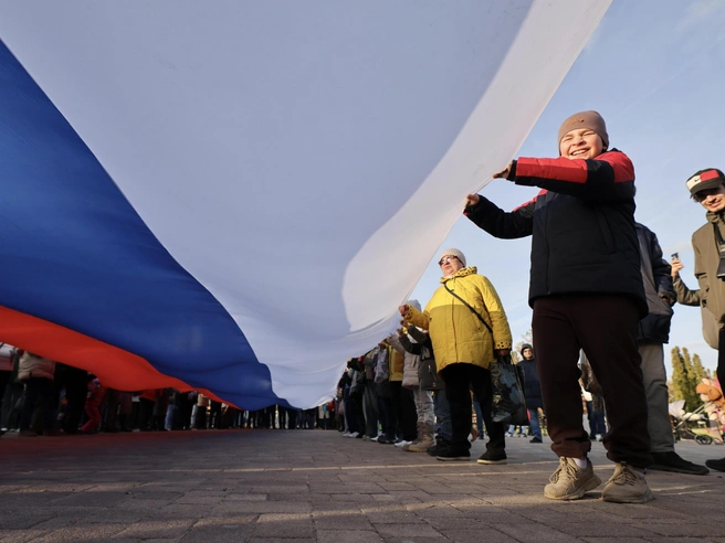 Гости помогали удерживать флаг during the патриотической акции | Источник: Алексей Волхонский / V1.RU