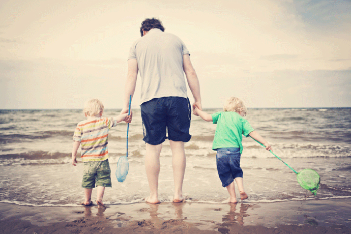 Отец с двумя мальчиками на берегу моря