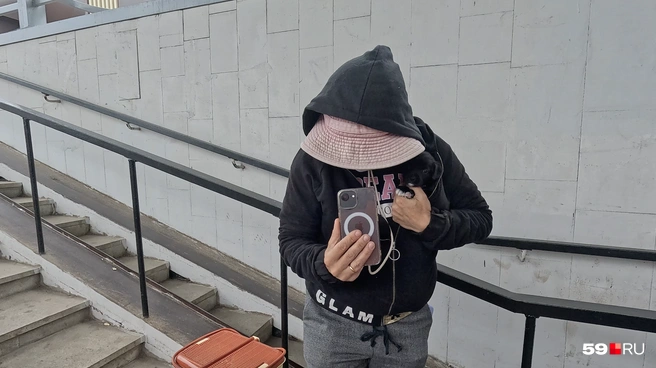 Судя по аксессуарам и одежде на женщине, она пытается скрыть свою личность, а в кармане виднеется второй телефон | Источник: Алексей Кожевников / 59.RU
