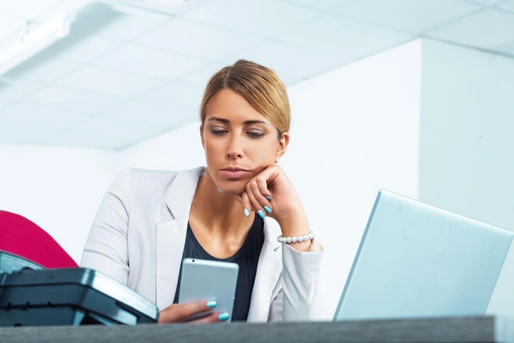 Бизнесвумен на работе смотрит на экран мобильного телефона | Источник: Giulio Fornasar / Alamy via Legion Media
