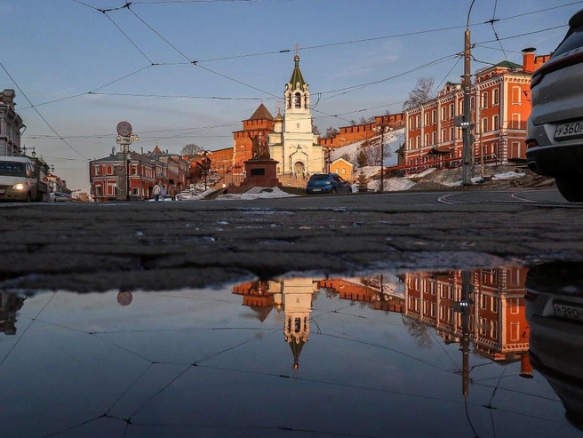 Отражение городского пейзажа в луже выглядит необычно и живописно. | Источник: Наталья Бурухина / NN.RU