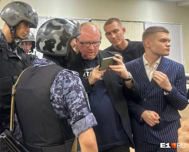 Один из руководителей RC Group Михаил Рутштейн показывает силовикам экран своего айфона | Источник: Анастасия Русанова / E1.RU