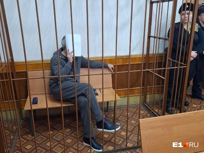 Гия Свердловский прятал свое лицо от журналистов за листом бумаги и черной папкой | Источник: Евгений Кошек / E1.RU