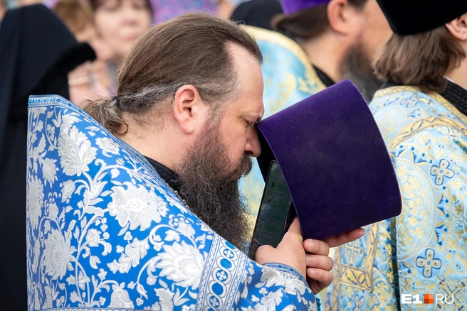 Даже на службе по случаю празднования явления чудотворной Тихвинской иконы Божией Матери святой отец не забывает про мирские иконки на экране телефона | Источник: Владислав Лоншаков / E1.RU
