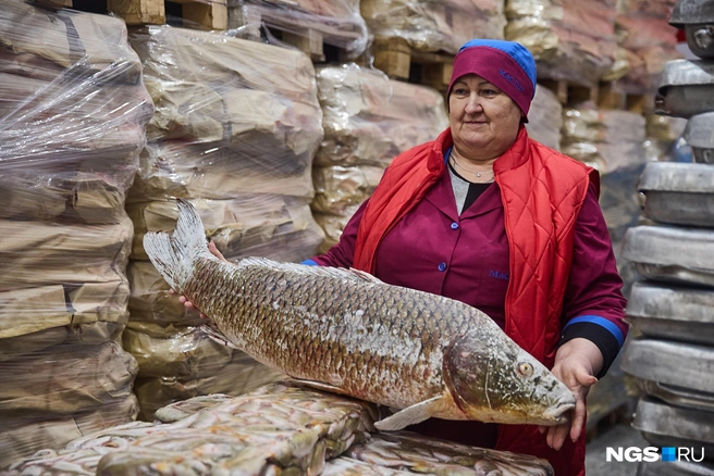 Мастер производства Наталья Колупаева демонстрирует крупную рыбу. Этого красавца поймали не сегодня и уже успели заморозить | Источник: Александр Ощепков / NGS.ru