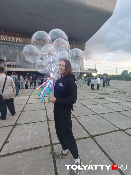 Девушка сначала гуляла с целой охапкой светящихся шаров, а потом их раздарила | Источник: Юлия Дроглева