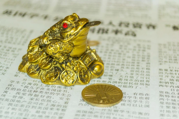 Денежная лягушка (Чан Чу), также называемая денежной трехногой жабой, всегда держит во рту одну китайскую монету. Денежная лягушка сидит на ложе из слитков и несет на спине цепочку из монет, символизирующую процветание и деньги | Источник: Mihai Popa / Alamy via Legion Media