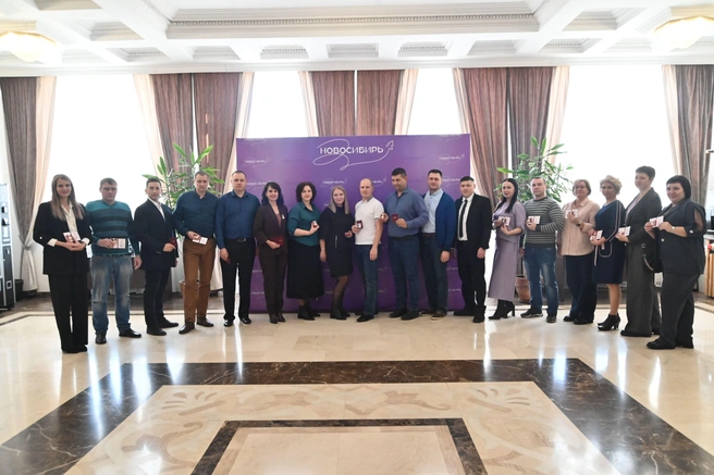 На знаке «Почетный донор России» изображены две капли крови (символизирующие донора и реципиента) на ладони на фоне расходящихся лучей | Источник: Nso.ru