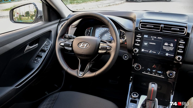 На руле — беззастенчивая эмблема Hyundai. Трехспицевый руль, непривычный селектор автомата и красная прострочка — атрибут топовой комплектации | Источник: Артем Краснов