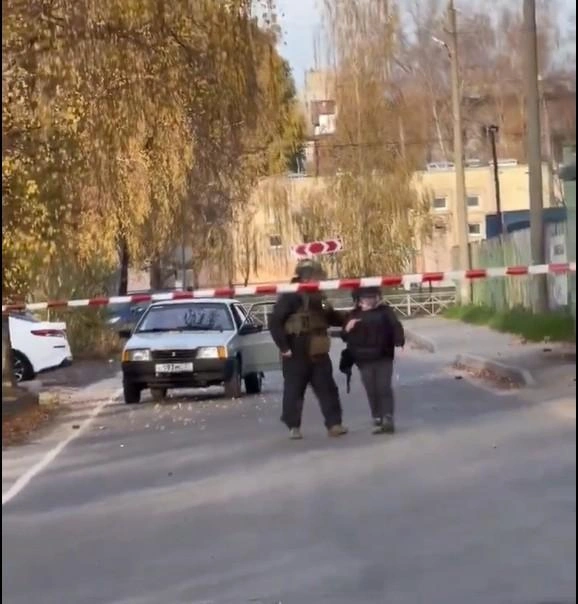 Сапер эвакуирует женщину из машины, вокруг которой разбросана взрывчатка, предварительно надев на нее каску и бронежилет | Источник: Стоп-кадр с видео. Егор Ковальчук / max.ru