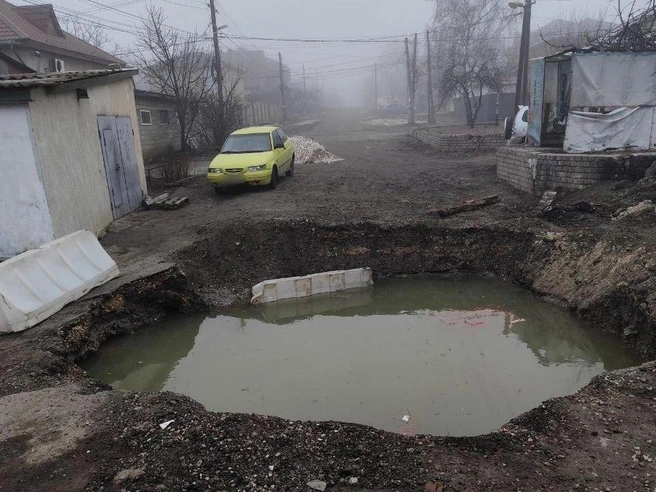 Наливные блоки, ограждавшие яму, утонули в глубокой луже. | Источник: читатели V1.RU