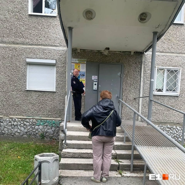 Сотрудники полиции останавливают и опрашивают соседей у входа в подъезд | Источник: Дарья Манохина / Е1.RU