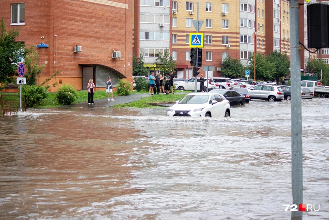 На месте разлива воды на дороге собралось немало зевак. Люди смотрели, как машины (да и Маша) преодолевали гигантскую лужу  | Источник: Павел Красоткин / 72.RU