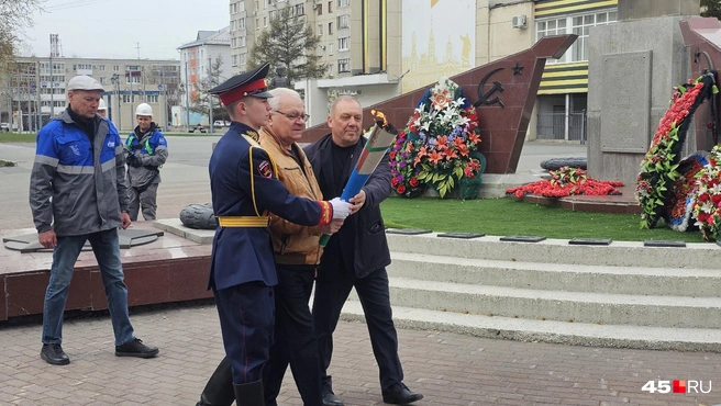 Ученик школы № 75 Илья Сотников, председатель городского совета ветеранов Владимир Дударев и генеральный директор АО «Газпром газораспределение Курган» Олег Попов переносят пламя Вечного огня | Источник: Дарья Никитченко / 45.RU