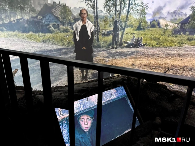 На экране актриса рассказывает о приходе нацистов в деревни. Под ее ногами — нарезка из фильма Климова «Иди и смотри» | Источник: Максим, читатель MSK1.RU