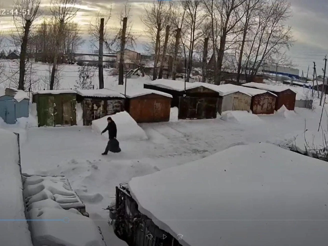 На записи с камеры видно, как неизвестный с чёрным мешком проходит мимо, а через мгновение возвращается обратно уже без ноши. | Источник: Татьяна Емельянова