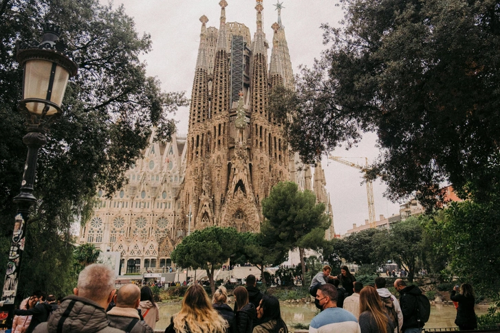 Саграда Фамилия (Basilica de la Sagrada Familia) в Барселоне — один из самых узнаваемых архитектурных шедевров мира. Его первый проект разработал Франсиско дель Вильяр в традиционном неоготическом стиле. Но когда в 1883 году проект возглавил Антонио Гауди, он изменил концепцию, объединив неоготические элементы — стрельчатые арки, башни-шпили, витражи — с органическими формами модерна. | Источник: Colin Meg/Unsplash
