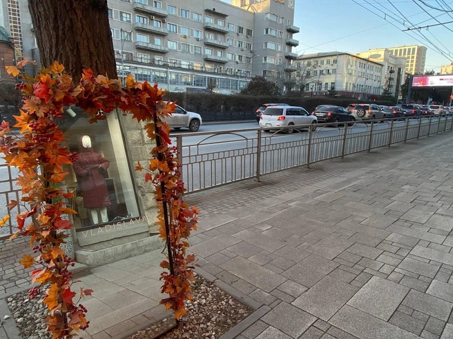 С начала октября возле магазина одежды на Красном проспекте установили зеркало в раме из жёлтых и красных искусственных листьев. | Источник: Анастасия Хрипушина/NGS.RU