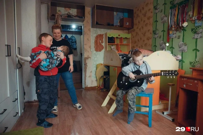 Илья&nbsp;— сын Натальи, с ее маленькой внучкой Евдокией, Алексей играет на гитаре | Источник: Иван Митюшёв / 29.RU
