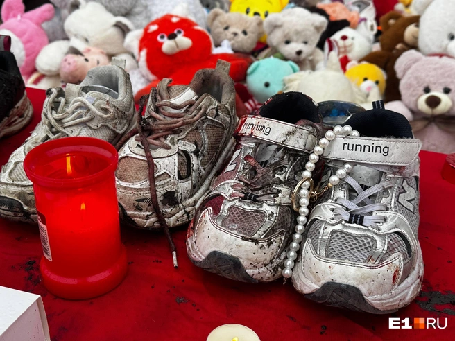 Обувь погибших девочек на столе с цветами и лампадами | Источник: Роман Марьяненко / E1.RU