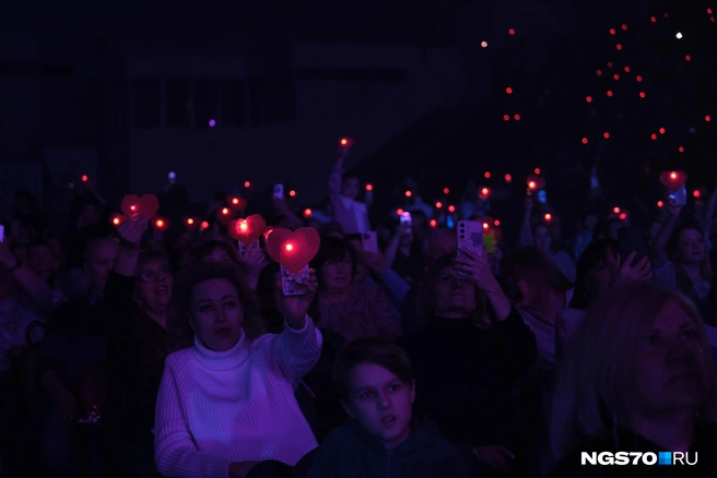 В начале мероприятия зрителям раздали сердечки, в которых предлагалось присоединться на конкретной песне к флешмобу&nbsp;— прицепить бумагу на телефон и включить фонарик. Многие поддержали идею | Источник: Василиса Орлова / NGS70.RU