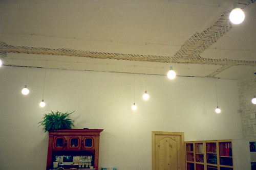 Высокие потолки украшает множество электрических лампочек, висящих на длинных проводах.