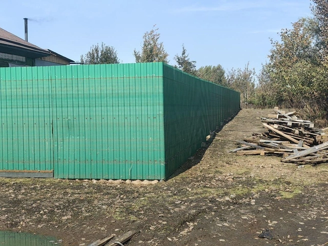 Забор в человеческий рост. Уровень воды доходил почти до края забора&nbsp;— коричневые полосы указывают на это | Источник: Павел Красоткин / 72.RU 
