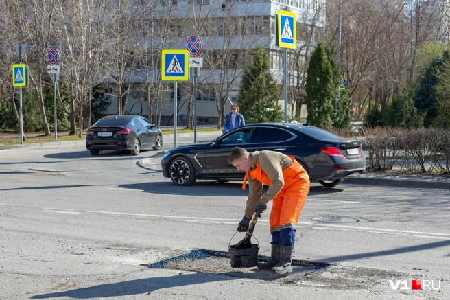 Ямы смазываются битумом с помощью простого соломенного веника | Источник: Константин Завриков / V1.RU