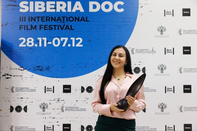 Нина Изотова держит статуэтку победителя фестиваля в виде лодки. Она сделана из старых деревьев сибирской тайги | Источник: Нина Изотова