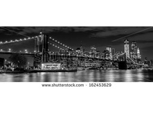 Stock-photo-brooklyn-bridge-with-manhattan-skyline-in-the-background-at-night-in-black-and-white-162453629.jpg